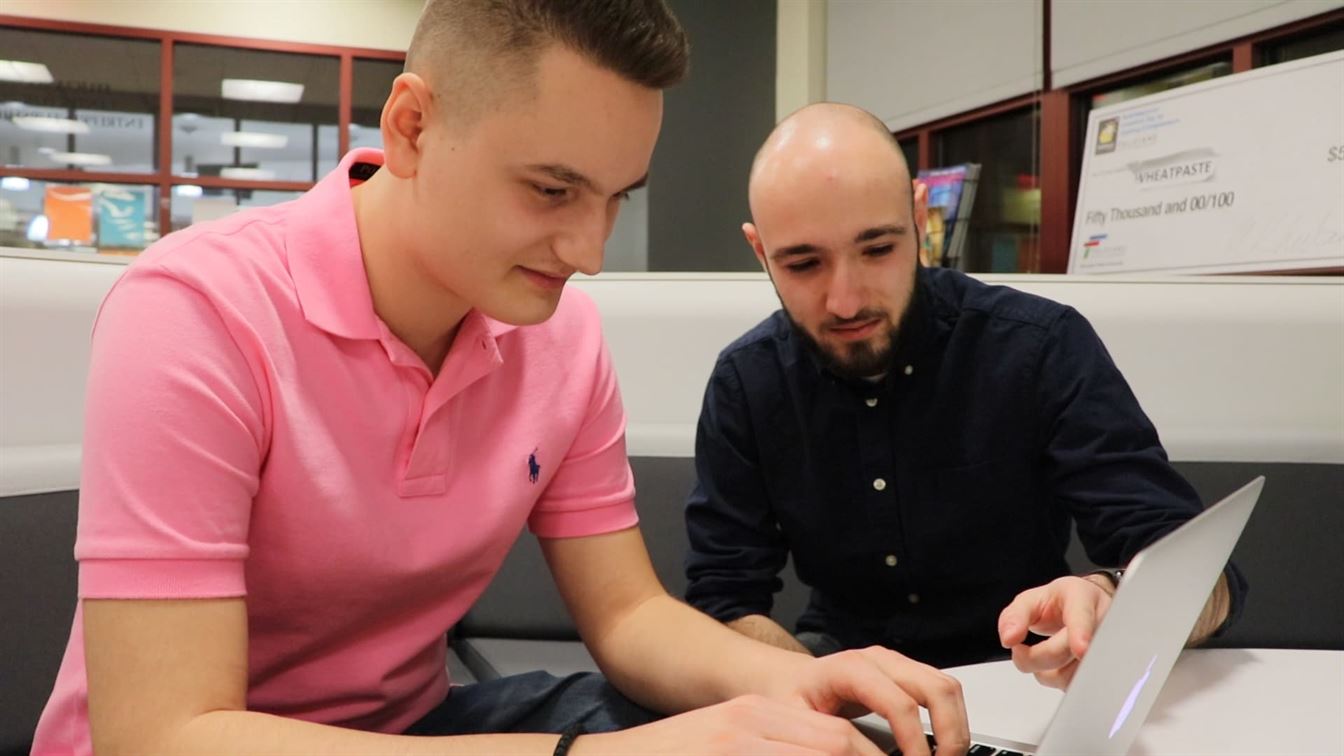 2 students looking at a laptop screen